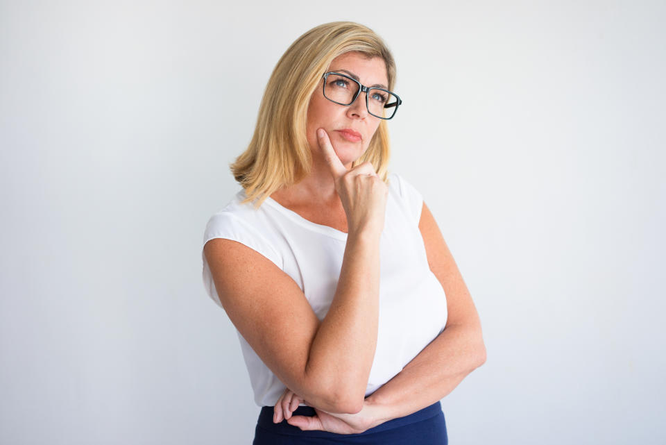 A woman in glasses ponders a decision.