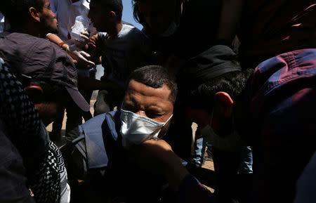 A wounded Palestinian journalist is evacuated during a protest marking al-Quds Day, (Jerusalem Day), at the Israel-Gaza border in the southern Gaza Strip June 8, 2018. REUTERS/Ibraheem Abu Mustafa