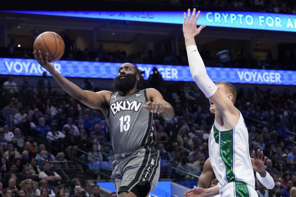 Brooklyn Nets guard James Harden (13) gets past Dallas Mavericks center Kristaps Porzingis, right, for a shot in the second half of an NBA basketball game in Dallas, Tuesday, Dec. 7, 2021. (AP Photo/Tony Gutierrez)