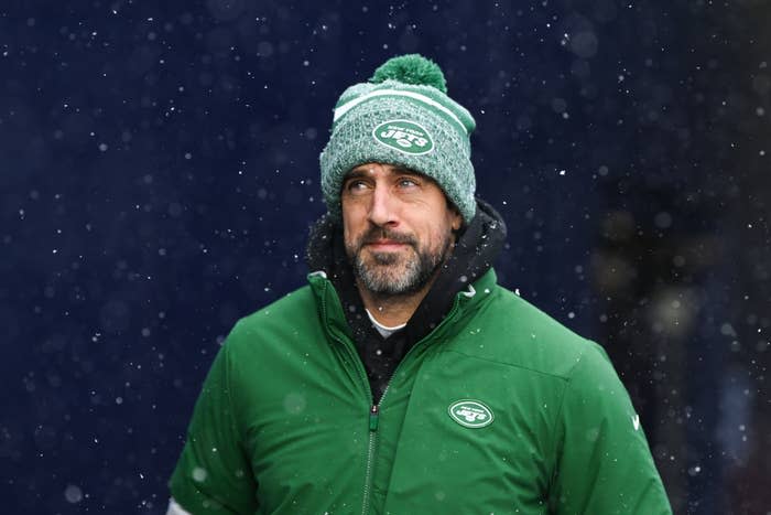 Man in a New York Jets beanie and green jacket standing in the snow