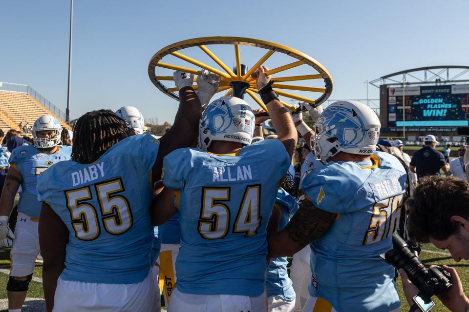 The Kent State Golden Flashes hoist the Wagon Wheel after defeating the University of Akron Zips 33-27 on Saturday at Kent State University’s Dix Stadium.