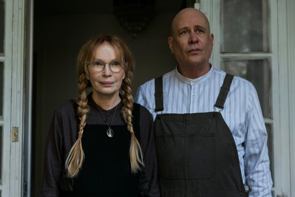 Mia Farrow in pigtails as Pearl Winslow and Terry Kinney as Jasper Winslow in overalls standing in a doorway in "The Watcher"