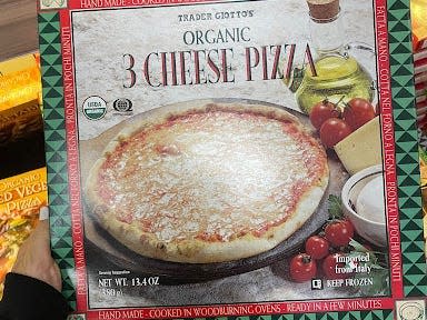 hand holding box of trader joe's frozen cheese pizza