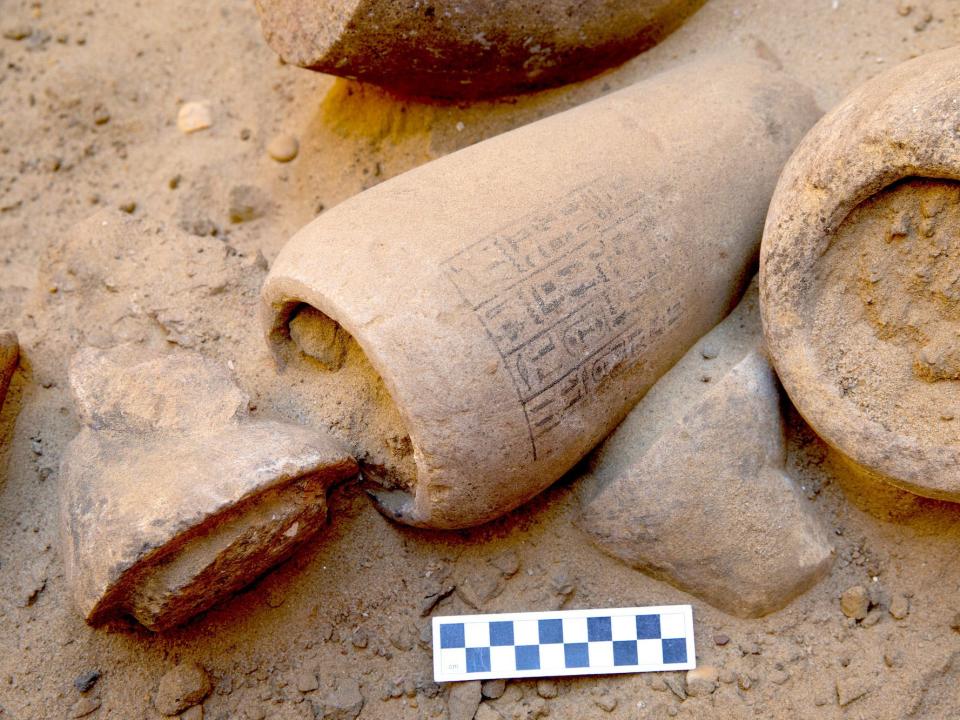 A jar is shown as found at the Abusir site, opened, with the lid having some sort of animal head on it and the body being covered with hieroglyphics.