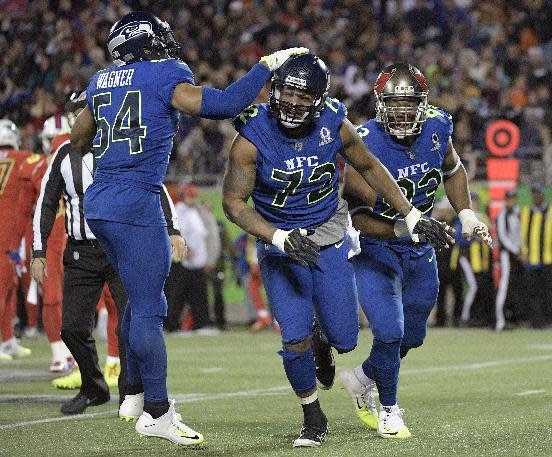 NFC linebacker Bobby Wagner (54), of the Seattle Seahawks congratulates defensive end Michael Bennett (72), of the Seattle Seahawks, after Bennett sacked AFC quarterback Andy Dalton (14), of the Cincinnati Bengals, during the first half of the NFL Pro Bowl football game Sunday, Jan. 29, 2017, in Orlando, Fla. To the right is NFC interior lineman Gerald McCoy (93), of the Tampa Bay Buccaneers. (AP Photo/Phelan M Ebenhack)