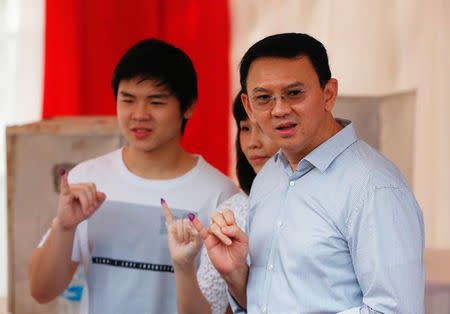 Incumbent Governor Basuki “Ahok” Tjahaja Purnama holds up his ink stained finger along with his wife Veronica Tan and his son Nicholas (L) after casting his vote the Jakarta governor election in North Jakarta, Indonesia April 19, 2017. REUTERS/Darren Whiteside