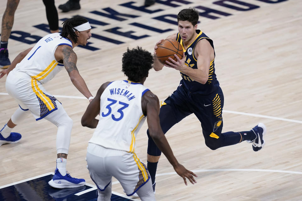 Indiana Pacers' Doug McDermott (20) goes to the basket against Golden State Warriors' Damion Lee (1) and James Wiseman (33) during the first half of an NBA basketball game Wednesday, Feb. 24, 2021, in Indianapolis. (AP Photo/Darron Cummings)