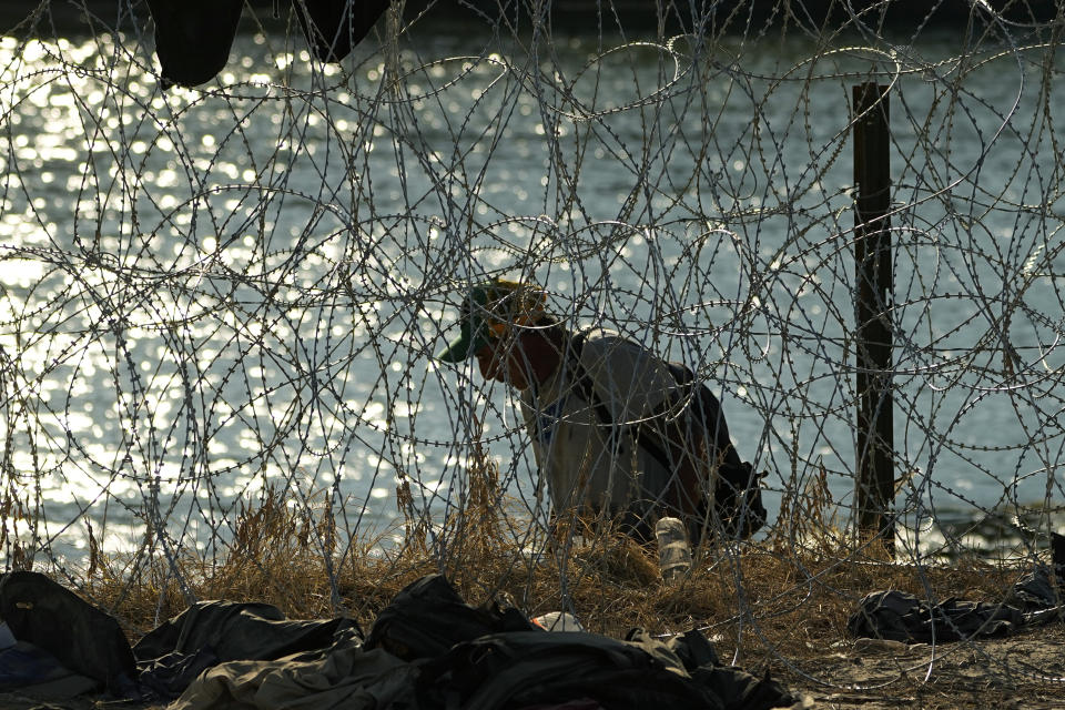 Un migrante que cruzó el Río Bravo desde México a Estados Unidos busca una forma de cruzar los alambres con concertinas, o cuchillas pequeñas, el 22 de septiembre de 2023, en Eagle Pass, Texas. (AP Foto/Eric Gay)