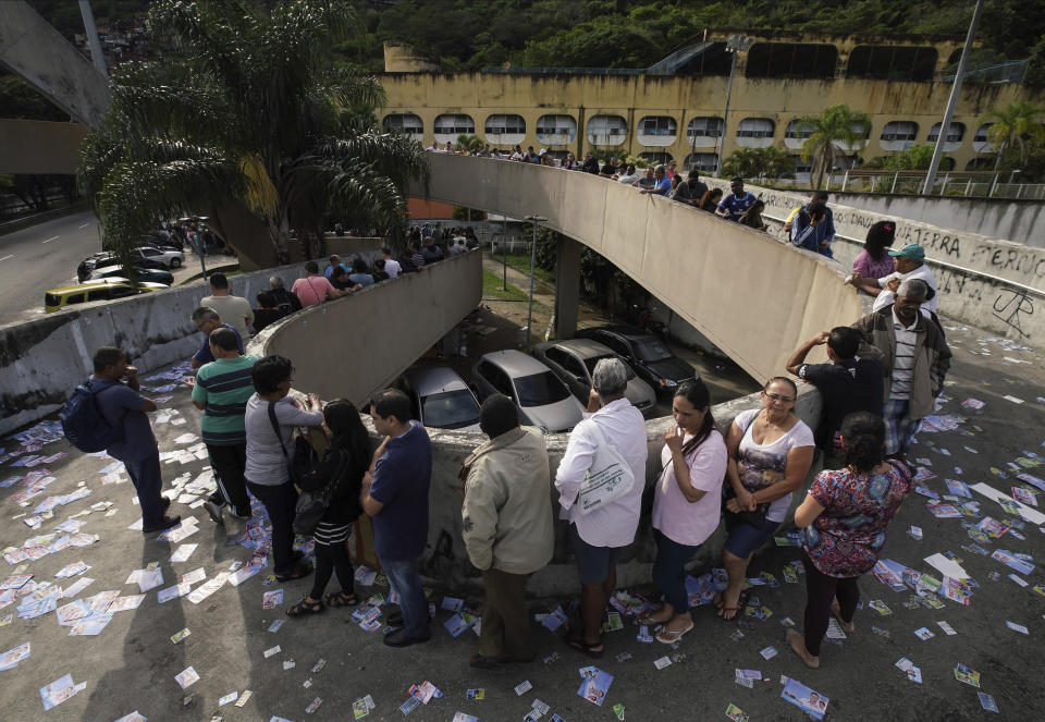 Voters wait in line at a polling station in the Rocinha favela in Rio de Janeiro, Brazil, Sunday, Oct. 7, 2018. Brazilians choose among 13 candidates for president Sunday in one of the most unpredictable and divisive elections in decades. If no one gets a majority in the first round, the top two candidates will compete in a runoff. (AP Photo/Ricardo Borges)