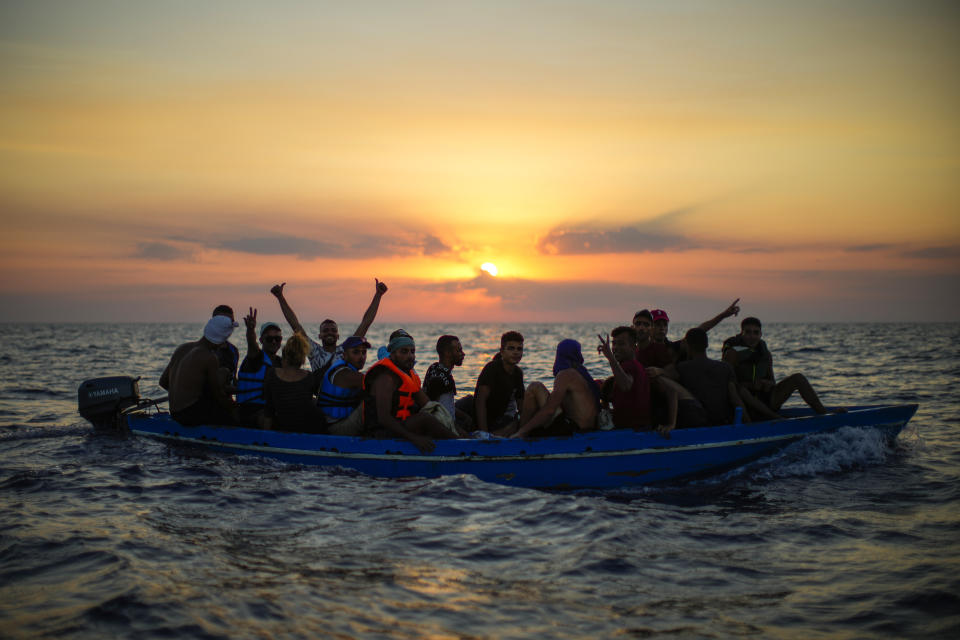 FILE - Migrants from Tunisia gesture as they sail in a wooden boat as they are assisted by crew members of the Spanish NGO Open Arms, sixteen miles west of the Italian island of Pantelleria in the Mediterranean sea, on Friday, Aug. 5, 2022. The Tunisian government is trying to tamp down criticism, and denunciations of racism, after President Kais Saied shocked many citizens _ and frightened some Africans here _ by saying that the presence of sub-Saharan migrants was part of a plot to transform the country into a "purely African" state, erasing its Arab and Islamic identity. (AP Photo/Francisco Seco, File)