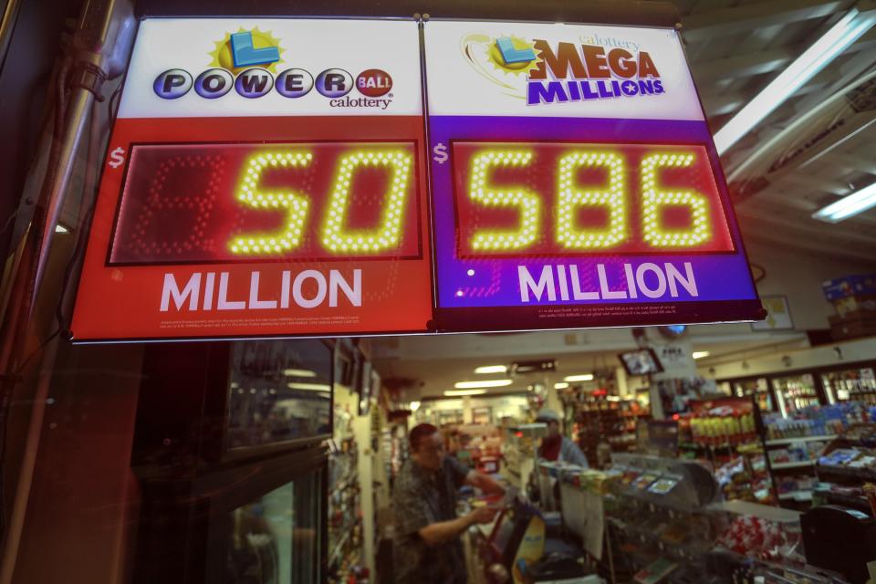 A worker at Nick's Liquor Store sells lottery tickets as a sign shows the Mega Millions jackpot estimated at $586 million in Venice, California December 16, 2013. The U.S. Mega Millions jackpot has grown to an estimated $586 million making it the second-largest drawing on record when the winning numbers are chosen on the night of Tuesday. REUTERS/Jonathan Alcorn (UNITED STATES - Tags: SOCIETY WEALTH)