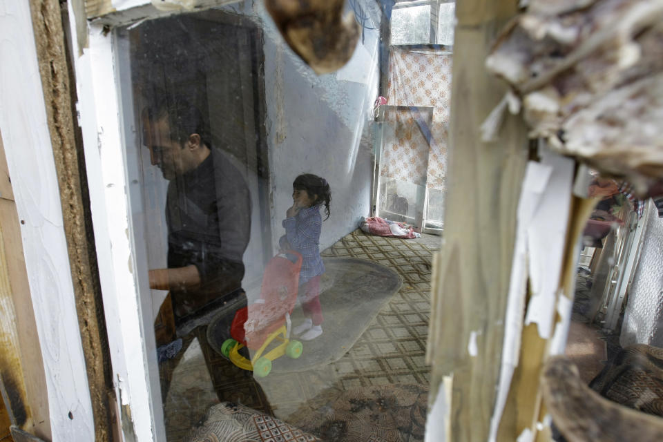 The unexpected movie star, Nazif Mujic, and his daughter Sandra walk in the porch of their shabby home in the village of Poljice, 150 kms northeast of Sarajevo, on Wednesday, April 10, 2013. People in the Gypsy village of Poljice say they will never forget the night they almost fell off their chairs two months ago. Did they really hear the elegant woman on TV correctly? Could she really be talking about their neighbor, the toothless man who passed his days selling scrap metal and lived in the shack down the road? The camera switched to a frightened-looking Najif Mujic. Yes it was him. THEIR Nazif _ who had just left Matt Damon and Jude Law in the dust to win the best actor award at the Berlin Film Festival. (AP Photo/Amel Emric)