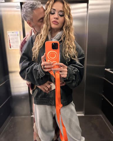 <p>Rita Ora/Instagram</p> Rita Ora takes a mirror selfie as husband Taika Waititi kisses her neck.