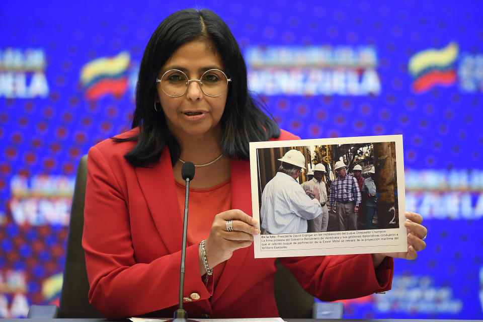 La vicepresidenta venezolana, Delcy Rodríguez, sostiene una foto con una leyenda que dice que el expresidente de Guayana, David Arthur Granger, se encuentra en el buque de perforación Deepwater Champion y exige que Exxon deje de perforar en un área en disputa, durante una conferencia de prensa en el palacio presidencial de Miraflores en Caracas, Venezuela, el lunes 11 de enero de 2021. (AP Foto/Matias Delacroix)