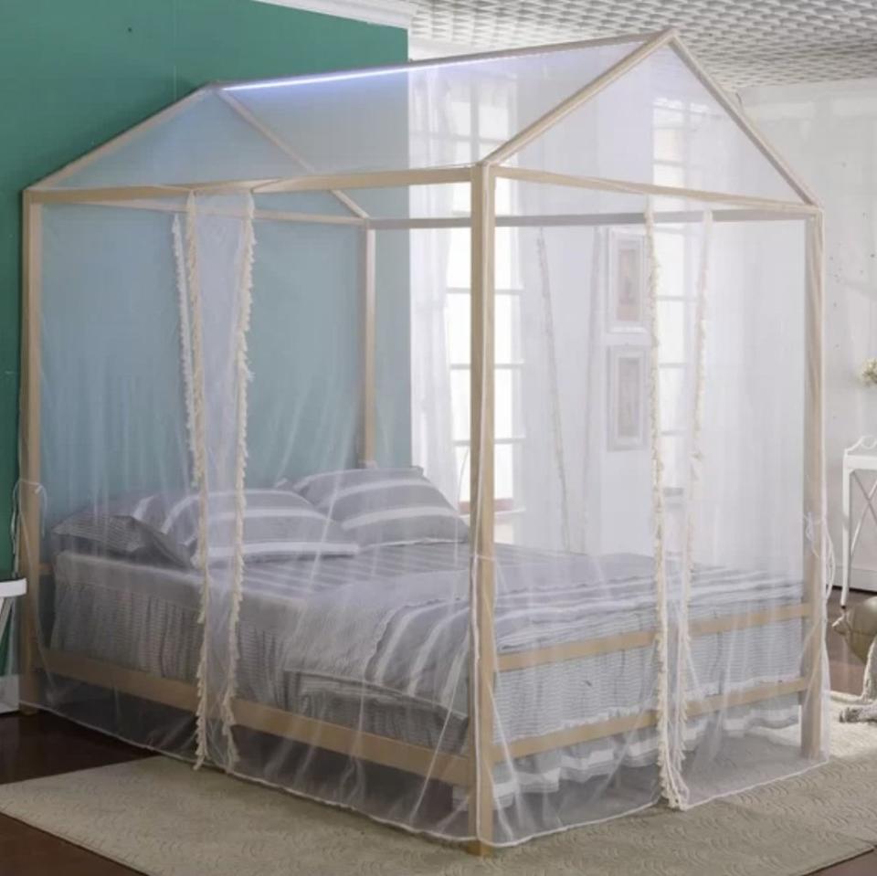 A child's canopy bed with grey linens