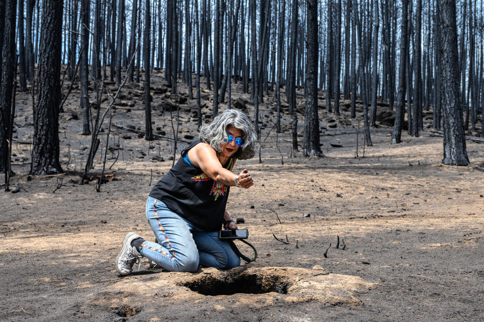 Pola Lopez sits by a hole where a ponderosa pine was vaporized by the Hermits Peak/Calf Canyon fire, noting the underground root tunnels leading away from it. - Credit: Michael Benanav/Searchlight New Mexico