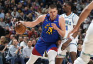 Denver Nuggets center Nikola Jokic, left, drives to the basket as Minnesota Timberwolves center Naz Reid defends in the first half of an NBA basketball game Friday, March 29, 2024, in Denver. (AP Photo/David Zalubowski)