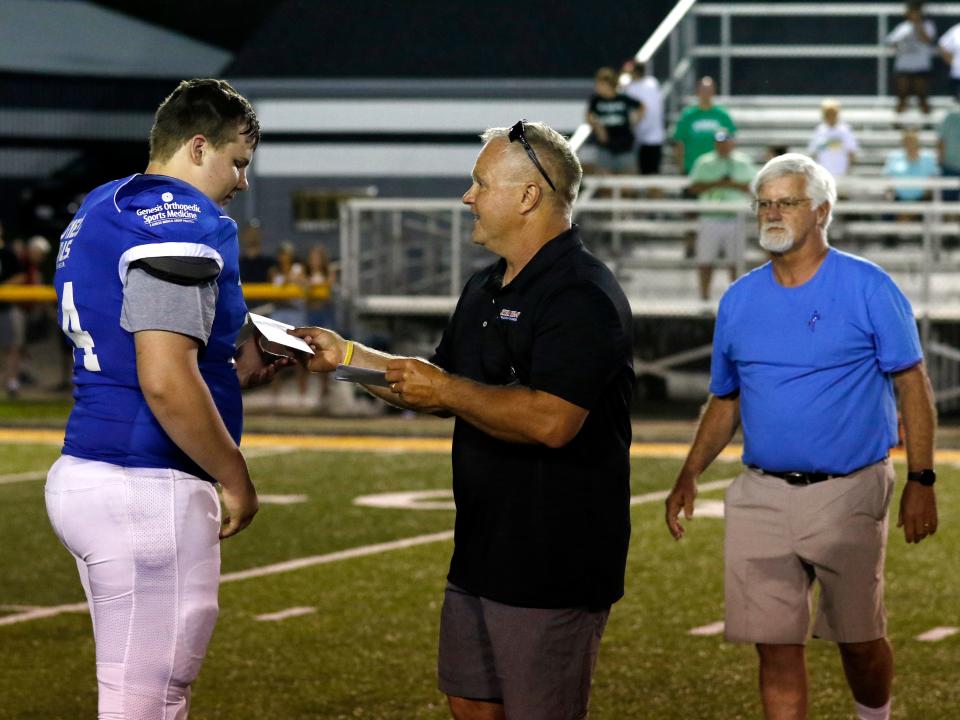 Muskingum Valley League commissioner Scott Welker gives the MVL Scholarship to Maysville's Garrett LaFollette following Muskingum Valley's 24-23 comeback win against Licking County in their 40th annual All-Star football clash at Jack Anderson Stadium in Dresden. Welker was recently inducted into the Ohio High School Athletic Association Officials Hall of Fame.