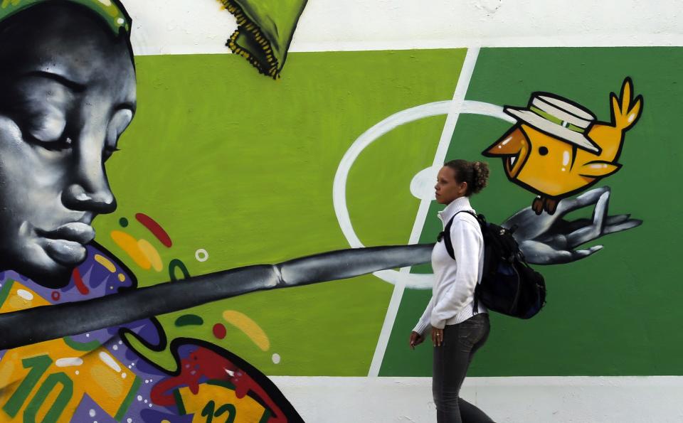 A woman walks past by graffiti painted on a wall in reference to the 2014 World Cup in Rio de Janeiro May 14, 2014. Rio de Janeiro is one of the host cities for the 2014 World Cup in Brazil. REUTERS/Sergio Moraes (BRAZIL - Tags: SPORT SOCCER WORLD CUP)