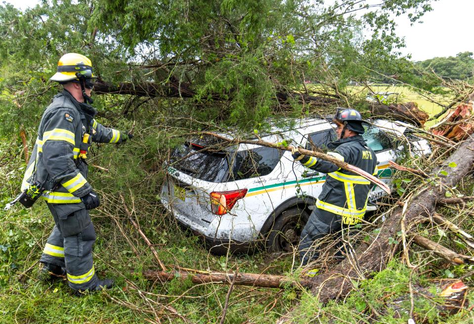 Marion County Fire Rescue Firefighter/EMT Jacob Knobbe, left, and Driver Engineer Matt Kimerling, right, clear out brush after responding to a single-vehicle crash that involved Marion County Sheriff's Deputy Jonathan Coleman Wednesday morning.