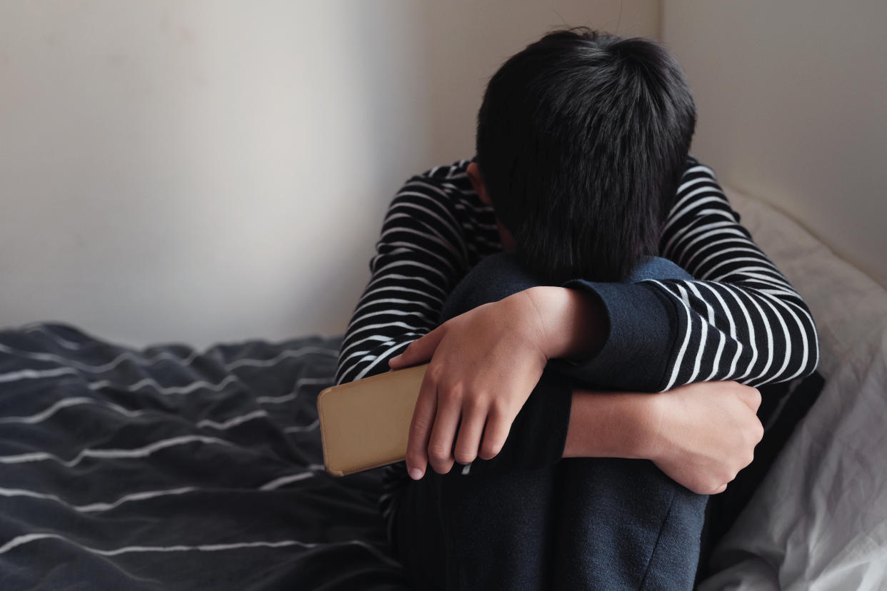 Young boy hugging his knees.