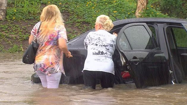 Women collecting their personal belongings from their car after driving into floodwater. Source: 7News