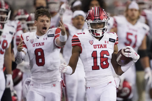 Utah safety Zemaiah Vaughn (16) runs 73 yards as quarterback Jake Bentley (8) reacts on the sideline after Vaughn intercepted a Washington pass during the first half of an NCAA college football game Saturday, Nov. 28, 2020, in Seattle. (AP Photo/Ted S. Warren)