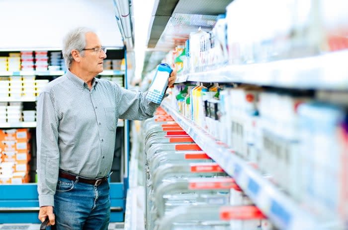 Mature man reads the label on a milk carton.