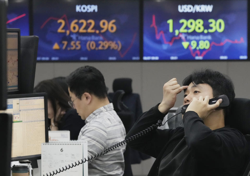 A currency trader talks on the phone near screens showing the Korea Composite Stock Price Index (KOSPI), top left, and the foreign exchange rate between U.S. dollar and South Korean won at the foreign exchange dealing room of the KEB Hana Bank headquarters in Seoul, South Korea, Wednesday, June 7, 2023. Asian shares were mixed Wednesday after a day of listless trading on Wall Street in the absence of market-moving data. (AP Photo/Ahn Young-joon)