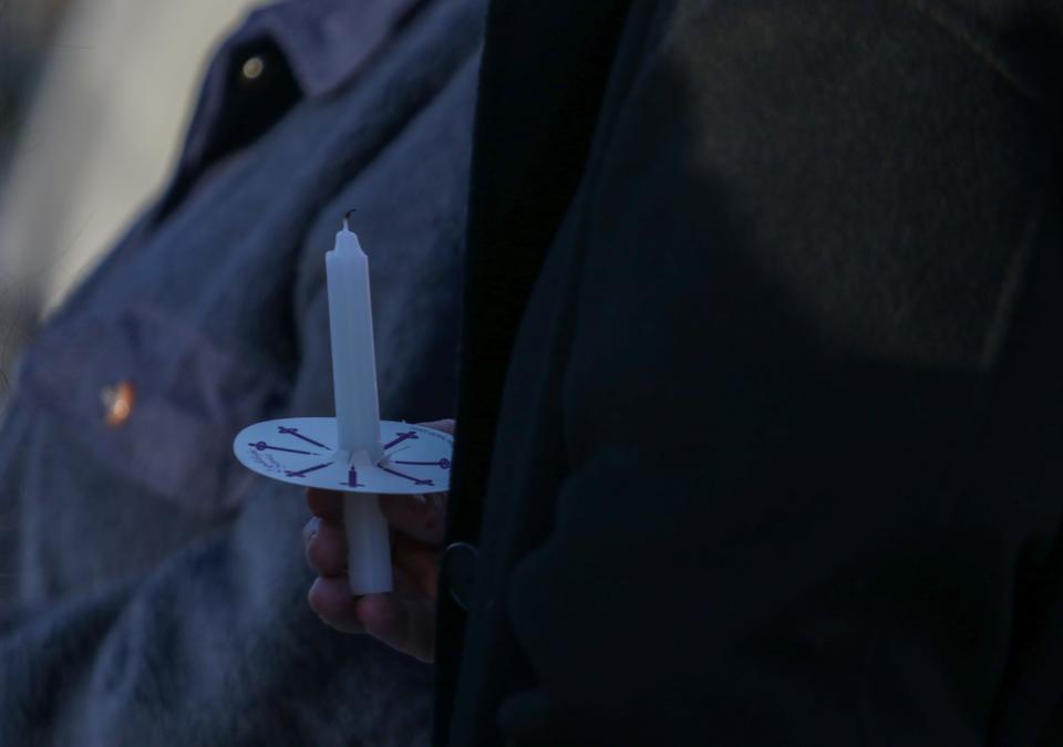 A person holds an unlit candle during the Homeless Person's Memorial vigil outside of the LTHC Homeless Service and the Salvation Army buildings, on Thursday, Dec. 21, 2023, in Lafayette, Ind.