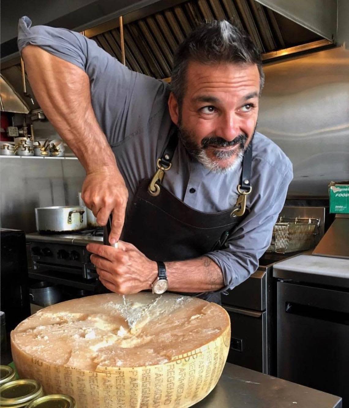 Chef Giancarlo “Wendy” Cacciatori and a very large wheel of cheese at his Miami Beach restaurant, Via Emilia 9.