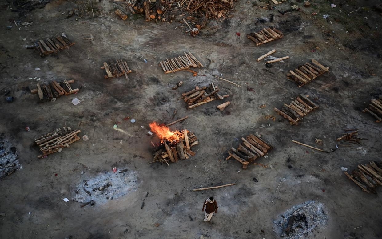 A worker walks near pyres for cremating the bodies of victims who died after contracting Covid-19 on the banks of the Ganges river in India - Ritesh Shukla/Getty Images