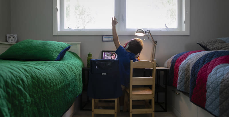 A student raises his hand while attending an online class from home in Miami, Florida, U.S., in September 2020. (Eva Marie Uzcategui/Getty Images)