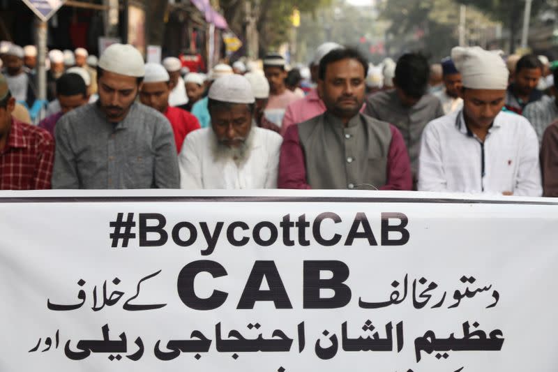 People offer Friday prayer in front of a banner before the start of a protest march against the Citizenship Amendment Bill in Kolkata