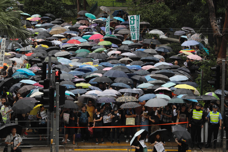 Pro-democracy protesters wait to cross a road during a march organized by teachers in Hong Kong Saturday, Aug. 17, 2019. Members of China's paramilitary People's Armed Police marched and practiced crowd control tactics at a sports complex in Shenzhen across from Hong Kong in what some interpreted as a threat against pro-democracy protesters in the semi-autonomous territory. (AP Photo/Vincent Yu)