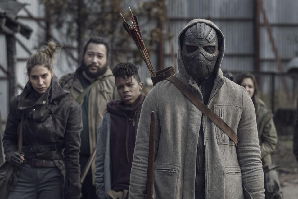 photo of Walking Dead survivors standing with masked character in front