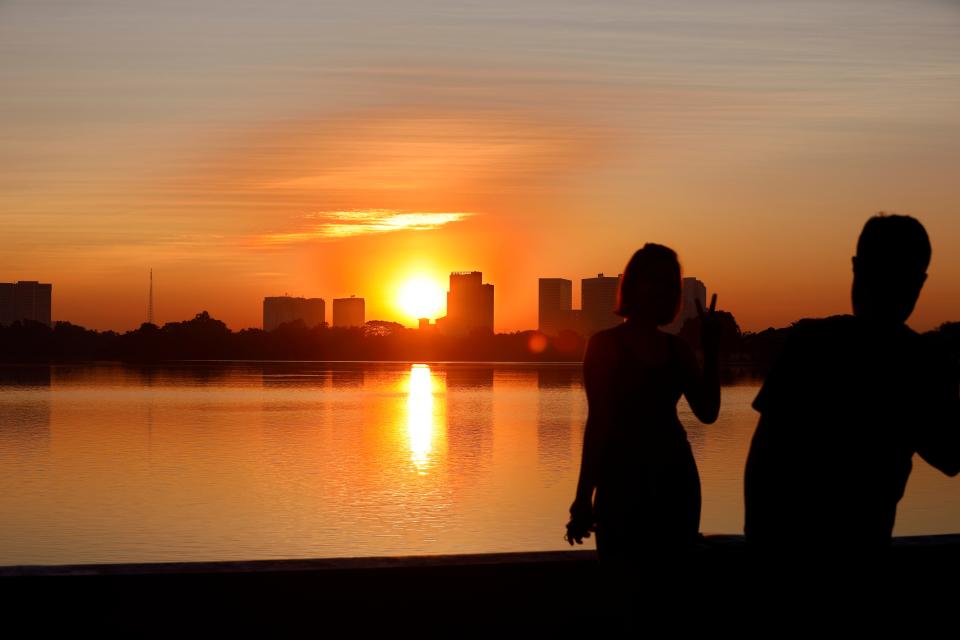 The sun rises on New Years Day as people  take photos with their mobile phone over the skyline of Yangon, Myanmar, 1 January 2024 (EPA)