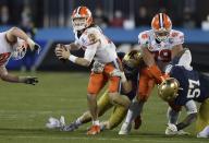 Clemson quarterback Trevor Lawrence (16) continues to look for a receiver as a Notre Dame defender wraps him up during the Atlantic Coast Conference championship NCAA college football game, Saturday, Dec. 19, 2020, in Charlotte, N.C. (Jeff Siner/The News & Observer via AP)