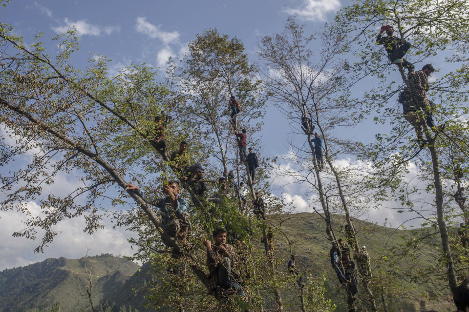 Kashmiri villagers climb trees to watch the funeral of top rebel commander Gulzar Ahmed Paddroo in Aridgeen, about 75 kilometers south of Srinagar, Indian controlled Kashmir, Saturday, Sept 15, 2018. Indian troops laid a siege around a southern village in Qazigund area overnight on a tip that militants were hiding there, police said. A fierce gunbattle erupted early Saturday, and hours later, five local Kashmiri rebels were killed. (AP Photo/Dar Yasin)