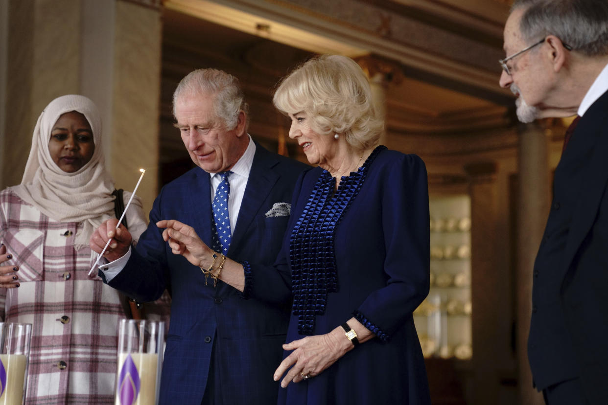 Britain's King Charles III and Camilla, the Queen Consort light two candles at Buckingham Palace, London, Friday, Jan. 27, 2023, to mark Holocaust Memorial Day, alongside Amouna Adam, left, a survivor of the Darfur genocide, and Holocaust survivor Dr Martin Stern, right. (Victoria Jones/Pool Photo via AP)