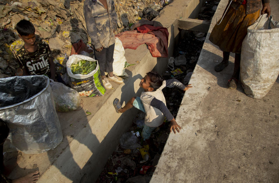 Imradul Ali, 10, center, plays as he looks for recyclable material at a landfill on the outskirts of Gauhati, India, Thursday, Feb. 4, 2021. Once school is done for the day, Ali, rushes home to change out of his uniform so that he can start his job as a scavenger in India’s remote northeast. Coming from a family of scavengers or “rag pickers," Ali started doing it over a year ago to help his family make more money. Ali says he doesn’t want to spend his life doing this, but he doesn’t know what the future holds. (AP Photo/Anupam Nath)