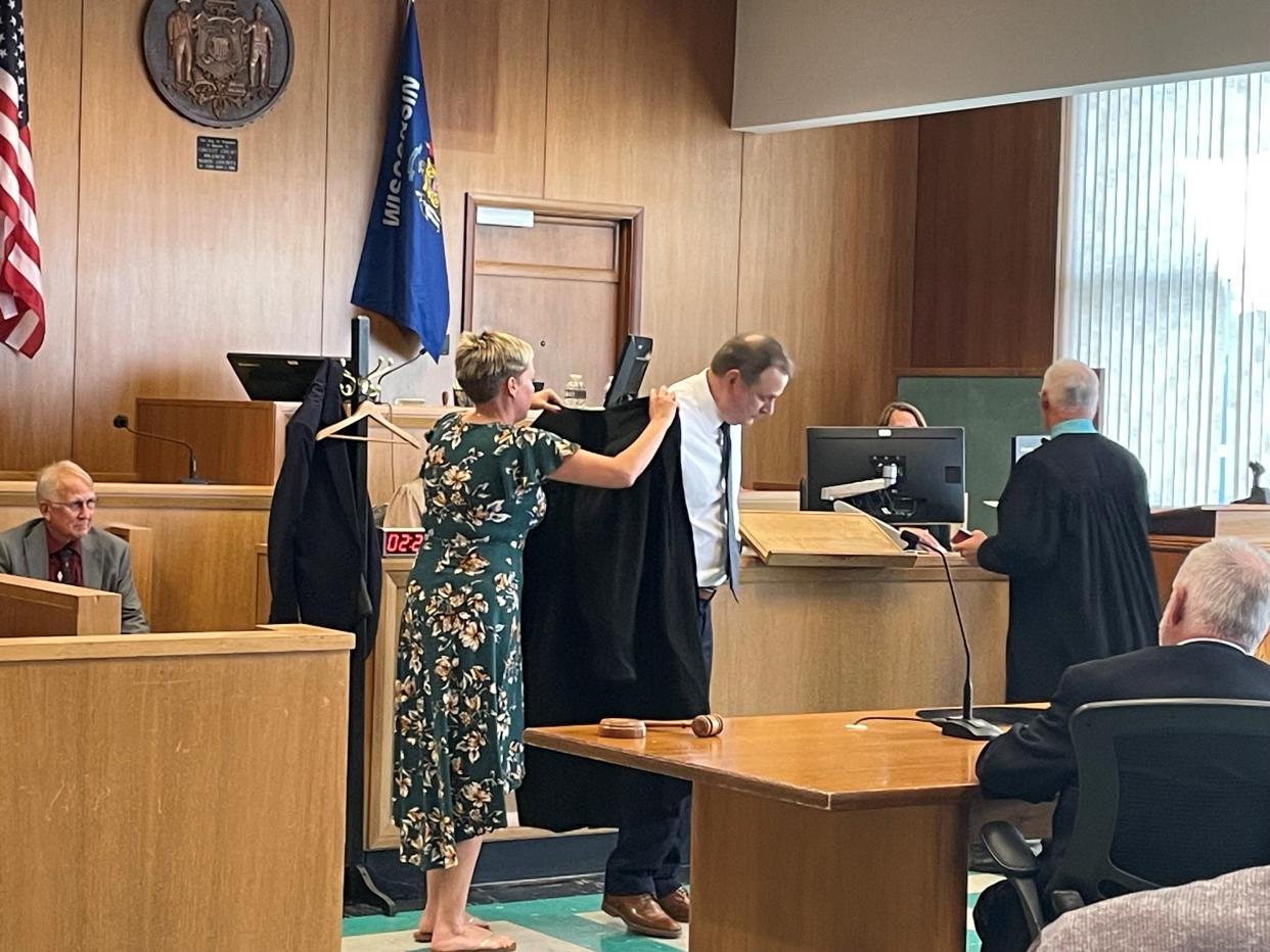 Elizabeth Gebert helps her husband, Tim Gebert, put on his judge's robe during his investiture ceremony Friday afternoon.