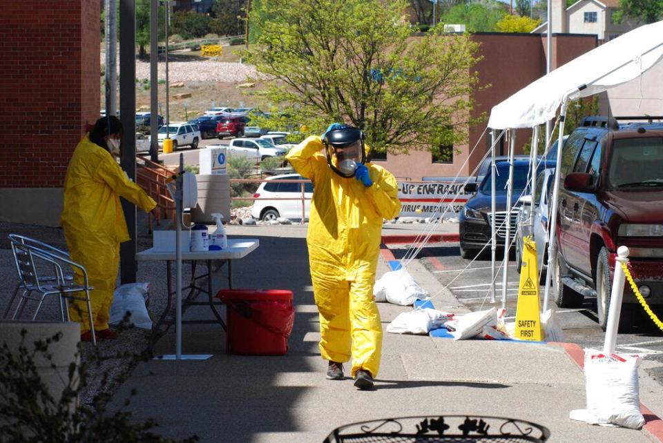 In this May 7, 2020, photo, medical staff from Rehoboth McKinley Christian Hospital put on protective equipment as they work at a drive-thru coronavirus testing site outside the hospital in Gallup, N.M. New Mexico had a nursing shortage even before the pandemic and advocates are now trying to convince lawmakers to boost funding to increase capacity at the state's nursing schools.