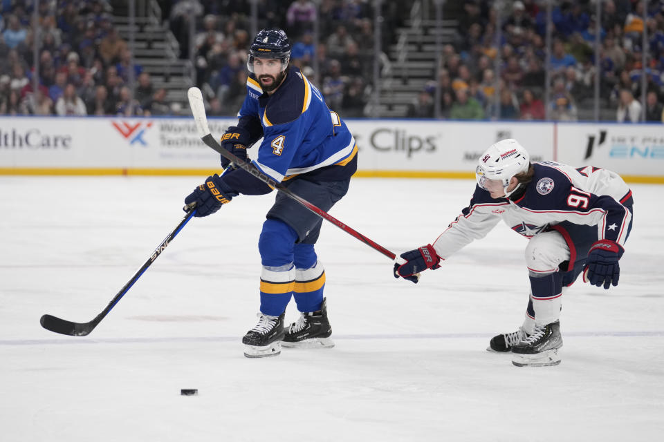 St. Louis Blues' Nick Leddy (4) and Columbus Blue Jackets' Kent Johnson (91) battle for a loose puck during the second period of an NHL hockey game Tuesday, Jan. 30, 2024, in St. Louis. (AP Photo/Jeff Roberson)