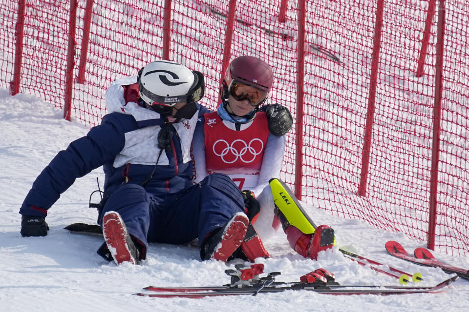 A team member consoles Mikaela Shiffrin, of the United States after she skied out in the first run of the women's slalom at the 2022 Winter Olympics, Wednesday, Feb. 9, 2022, in the Yanqing district of Beijing. (AP Photo/Robert F. Bukaty)