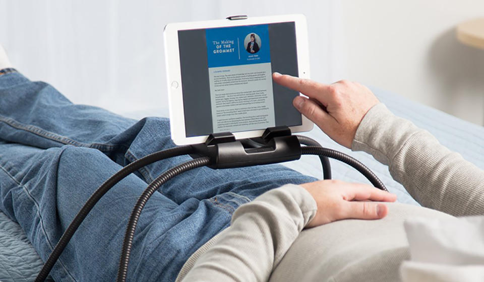 Man lying on his back with this stand across his lap and iPad attached to it.