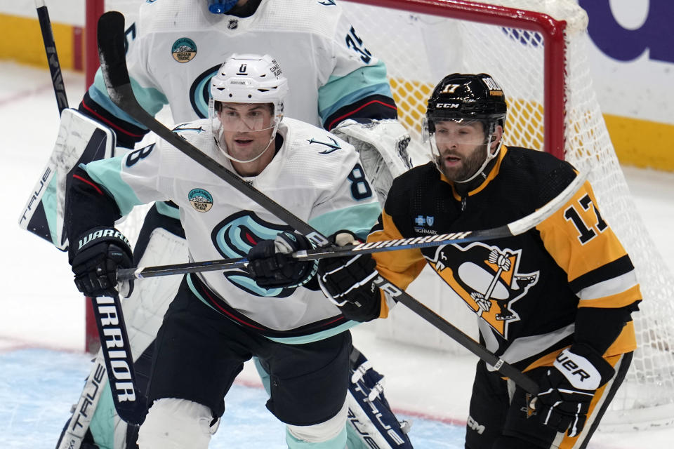 Seattle Kraken's Brian Dumoulin (8) defends Pittsburgh Penguins' Bryan Rust (17) in front of goalie Joey Daccord during the first period of an NHL hockey game in Pittsburgh, Monday, Jan. 15, 2024. (AP Photo/Gene J. Puskar)