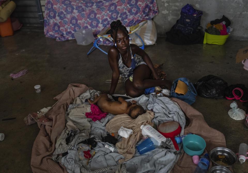 A woman sits next to her baby inside a classroom at a school converted into a makeshift shelter for people displaced by gang violence, in Port-au-Prince, Haiti, Wednesday, May 8, 2024. (AP Photo/Ramon Espinosa)