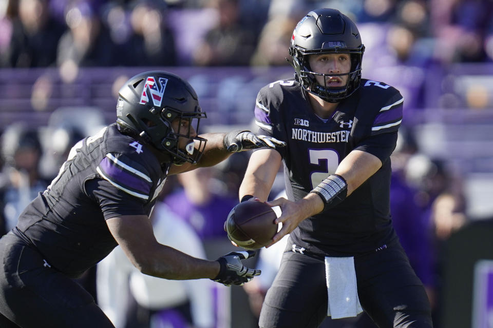 Northwestern quarterback Ben Bryant, right, hands the ball off to running back Cam Porter who runs in a touchdown during the first half of an NCAA college football game against Purdue, Saturday, Nov. 18, 2023, in Evanston, Ill. (AP Photo/Erin Hooley)