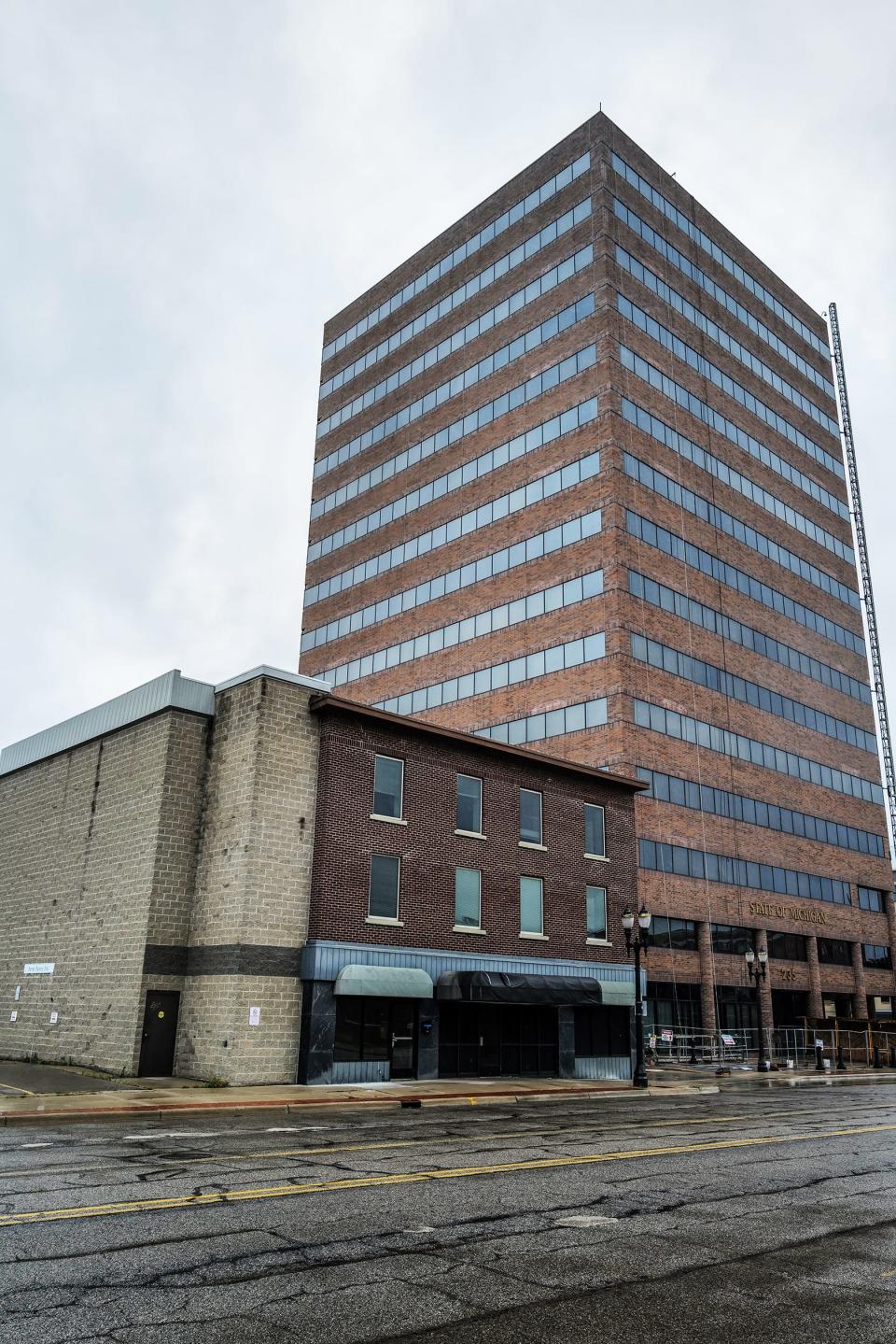 Next to the State of Michigan Tower on Grand Avenue, the plan is to tear down the smaller building and build a 25-story apartment and mixed-use tower that would cross over Grand Avenue. Photo: Sunday, Aug. 8, 2023.